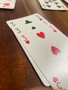 playing cards on a wooden table with red and black hearts