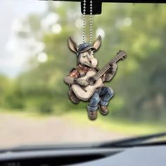 a keychain shaped like a kangaroo playing a guitar is hanging from the dashboard of a car