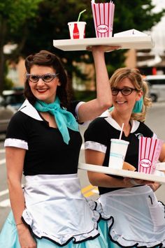 two women dressed as waitresses holding trays with drinks on them