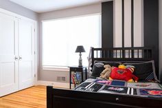 a bedroom with black and white stripes on the walls, wood floors and a bed