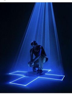 a man kneeling down in the middle of a room with blue light coming from it