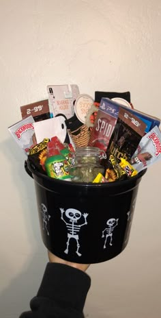 a person's hand holding a black bucket filled with candy