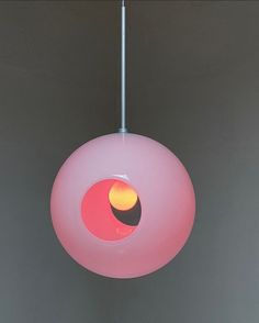 a pink light hanging from a ceiling in a room with grey walls and flooring