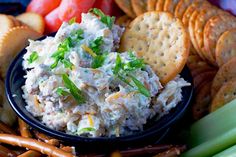 a bowl filled with chicken salad surrounded by crackers and vegetables