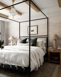 a bedroom with a four poster bed and two lamps on either side of the bed