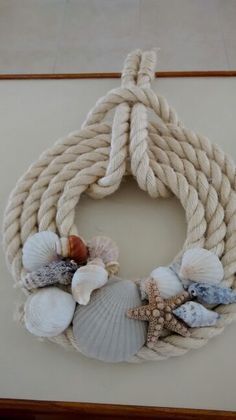 a rope wreath with seashells and shells hanging on the side of a wall