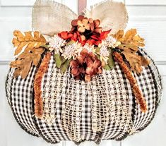 a black and white checkered pumpkin hanging from a front door with fall decorations on it