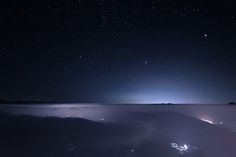 the night sky is filled with stars and light in the distance, as seen from an airplane