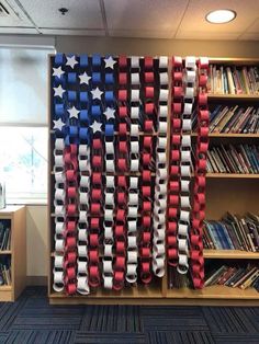 an american flag made out of red, white and blue ribbon hanging from a bookcase