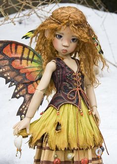 a doll dressed as a fairy holding a butterfly on her shoulder and wearing a yellow dress