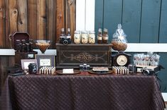 a table topped with lots of candies and other items next to a wooden fence