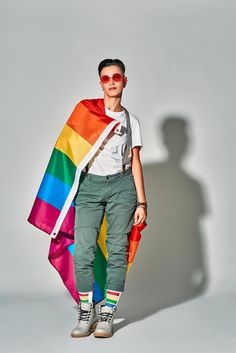 a man standing in front of a white wall with a rainbow scarf on his shoulders