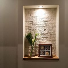 a vase with a plant in it sitting on a shelf next to a brick wall