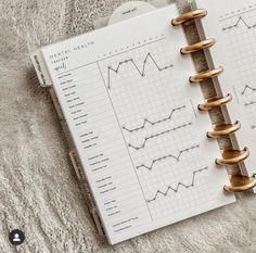 an open spiral - bound medical health book on top of a white blanket with gold handles