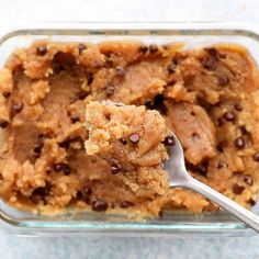 a spoon full of chocolate chip cookie dough in a glass dish with a scooper