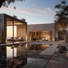 an outdoor swimming pool surrounded by rocks and trees at dusk with the sun setting on the horizon