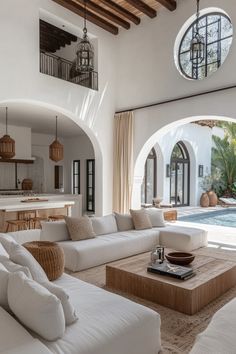 a living room filled with white furniture next to a swimming pool in a large house