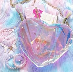 a pink heart shaped purse sitting on top of a fur covered floor next to other items