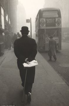 a man is walking down the street with a suitcase and a book in his hand