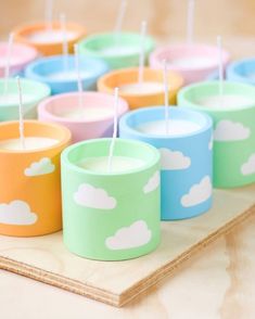 colorful cups with toothpicks in them sitting on a wooden tray, ready to be used as tea lights