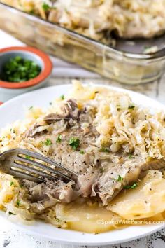 a white plate topped with pasta covered in gravy next to a casserole dish