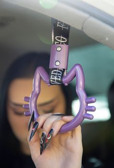 a woman holding up a purple object to her face in the back seat of a car