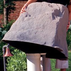 a woman standing next to a giant rock