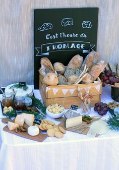 an assortment of breads and cheeses on a table with a sign in the background