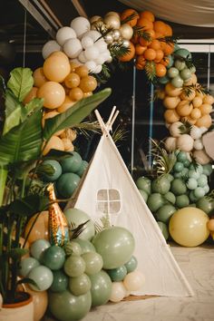 a teepee tent surrounded by balloons and greenery