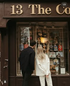 a man and woman standing in front of a store window