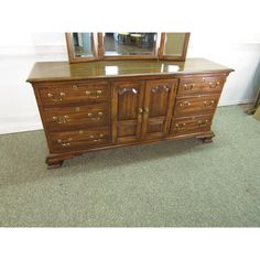 a large wooden dresser sitting on top of a carpeted floor next to a mirror