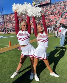 two cheerleaders holding up pom poms in front of an empty stadium