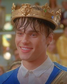 the young man is wearing a crown and smiling