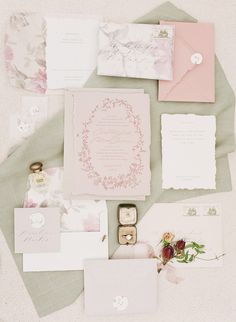 the wedding stationery is laid out on top of each other, including pink and white paper