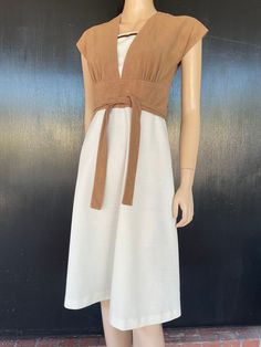 "1970s Jerell of Texas dress. Beige doe skin texture polyester bodice with cream polyester skirt . Panel in bodice matches skirt and has knit trim in shades of brown. Attached tie belts on sides wrap around to tie in front or back. Nylon zip back. Measurements are  34\" bust 26\" waist 36\" hips 16\" bodice length  42\" length Cute dress shows well, exhibiting minimal wear. Small dark (ink?) spot noted on skirt back by zipper edge as shown in pics." Retro Brown V-neck Dress, Fitted Belted Brown Midi Dress, Fitted Brown Belted Midi Dress, Retro Beige V-neck Dress, Brown Fitted Dress With Tie Waist, Fitted Brown Dress With Tie Waist, Beige V-neck Retro Dress, 1970s Fitted Beige Dress, Vintage Beige V-neck Midi Dress