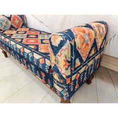 a colorful couch sitting on top of a hard wood floor next to a white bed