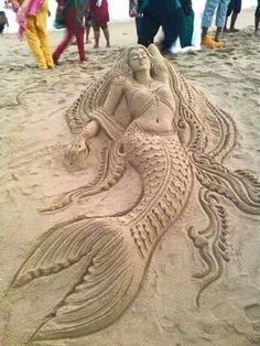 a sand sculpture of a mermaid on the beach