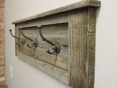 an old wooden coat rack with hooks on the wall next to a brick wall in a room