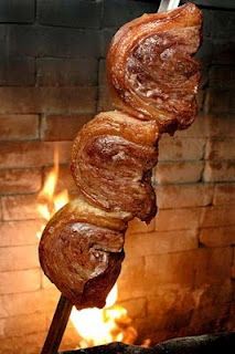 some food is being grilled on a stick in front of a brick fire place