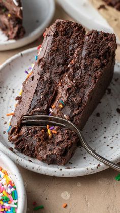 a piece of chocolate cake with sprinkles and a fork on a plate