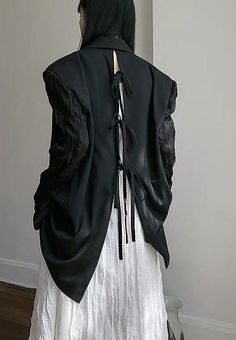 the back of a woman's black jacket with white laces and tassels