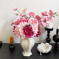 a white vase filled with pink flowers on top of a table