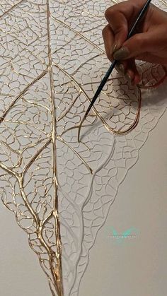 someone is working on something that looks like an intricate design with gold leafy details