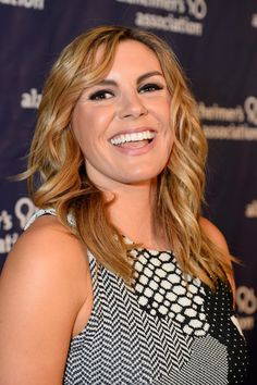 a woman with blonde hair smiling and wearing a black and white dress at an event