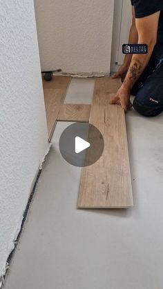 a man laying on the floor in front of a wall with wood planks and glue