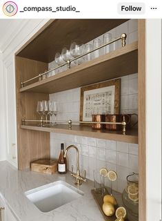 a kitchen with marble counter tops and shelves filled with wine glasses, lemons, and other items