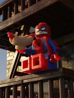 a lego spider man holding a hot dog in front of a building with iron bars