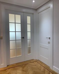 an empty room with white doors and wood floors