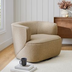 a living room with a coffee cup on the floor next to a chair and rug