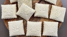 some white cookies sitting on top of a wooden plate next to other pieces of food